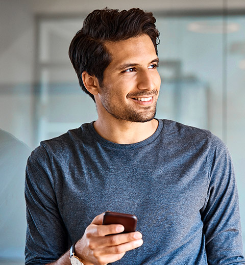 Man smiling while holding a cell phone